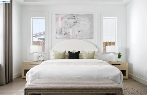 a large white bed sitting in a bedroom next to a window