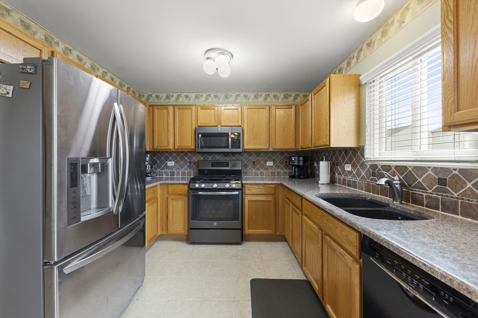 2217 Cedar Ridge Drive Plainfield, IL 60586 - Photo 7 of 26 a kitchen with stainless steel appliances a sink cabinets and a window