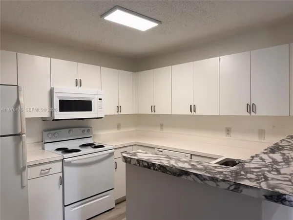 a kitchen with a refrigerator stove and white cabinets