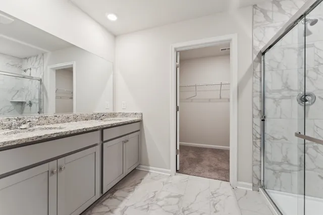 a bathroom with a granite countertop sink two mirror and shower