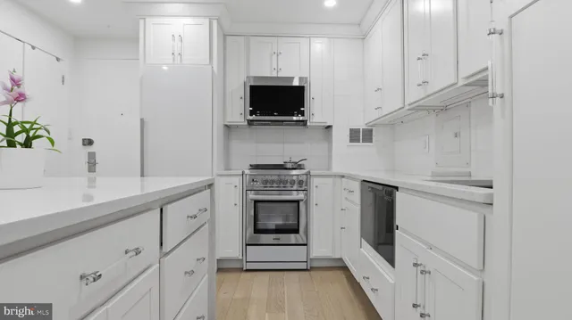 a kitchen with white cabinets and stainless steel appliances