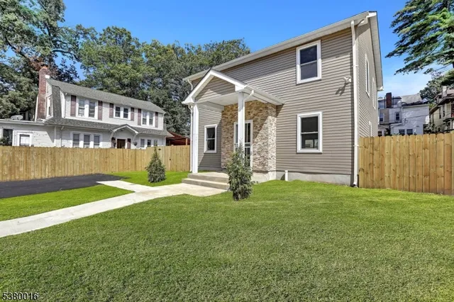 a view of a house with a yard and a large tree
