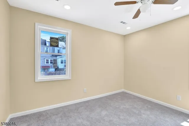 an empty room with a ceiling fan and window