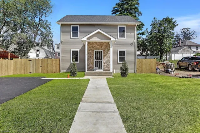 a front view of a house with a yard and trees