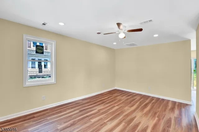 a view of a room with wooden floor and a ceiling fan