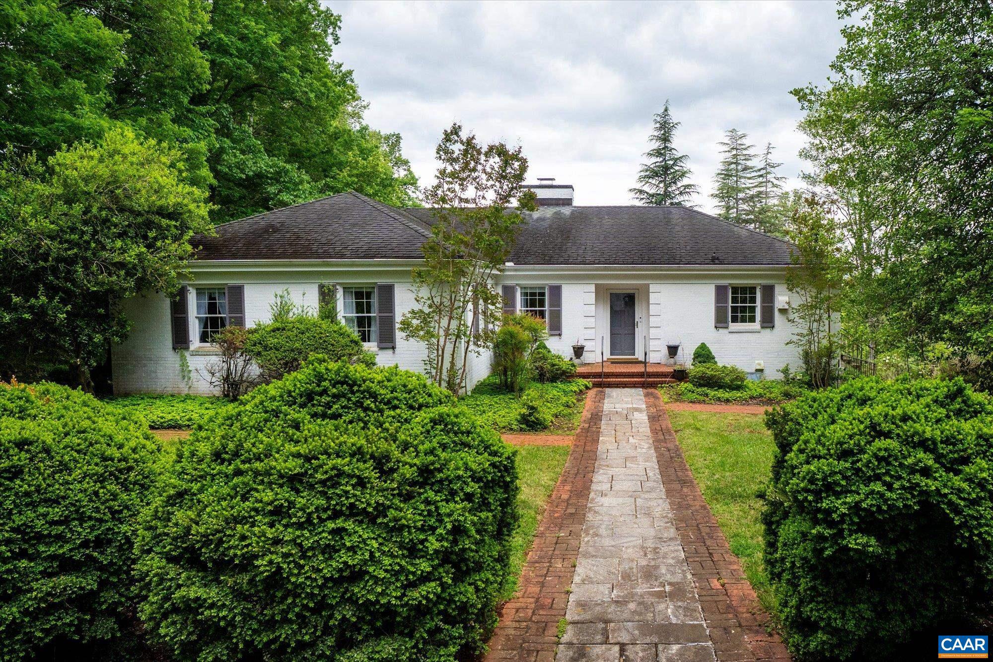 a view of a house with a small yard plants and large trees