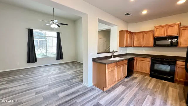 a kitchen with granite countertop wooden floors stainless steel appliances a sink and a window