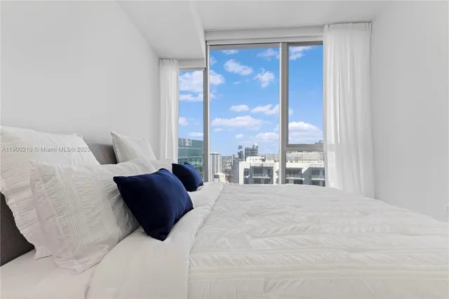 a large white bed sitting in a bedroom next to a window