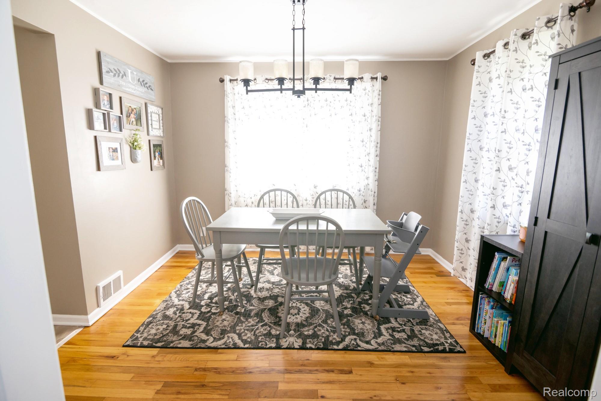 3757 Cone Avenue Rochester, MI 48309 - Photo 7 of 45 Bright dining area featuring wood-finish flooring, a contemporary chandelier, two windows with decorative curtains, and painted walls with white trim
