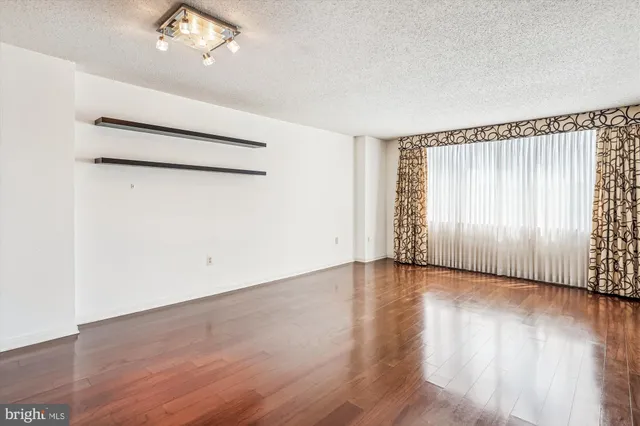 an empty room with wooden floor cabinet and windows
