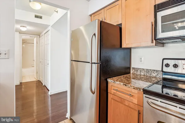 a kitchen with stainless steel appliances granite countertop a refrigerator a stove and a sink with wooden floor