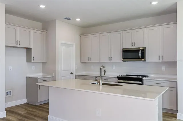 a kitchen with stainless steel appliances a sink a stove a microwave and wooden cabinets