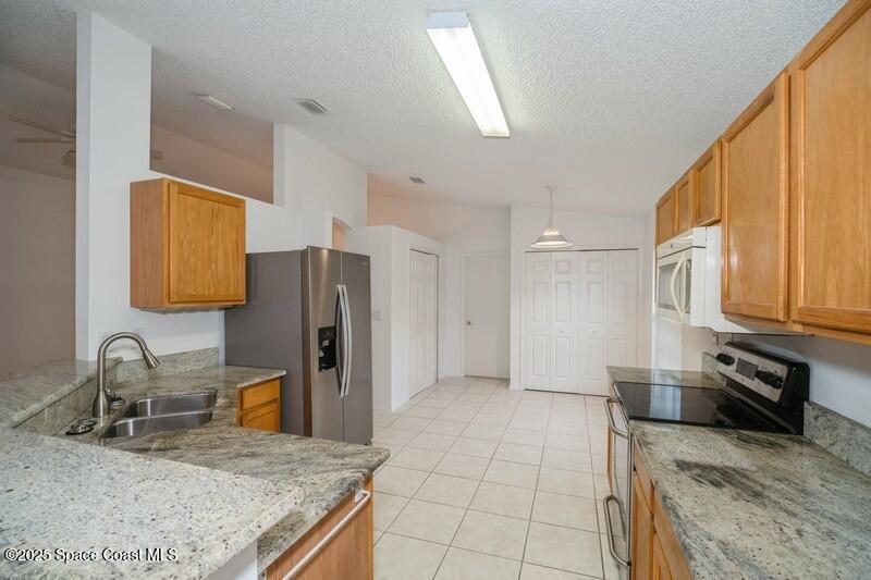 570 Benton Drive Melbourne, FL 32901 - Photo 6 of 26 a kitchen with granite countertop a sink a stove and refrigerator
