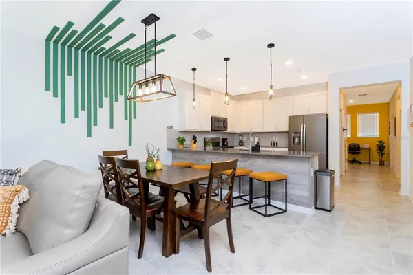 a kitchen with stainless steel appliances granite countertop a refrigerator a stove top oven a sink dishwasher a dining table and chairs with wooden floor