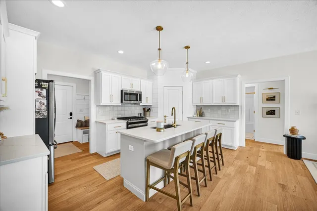 a kitchen with stainless steel appliances a dining table chairs stove refrigerator and cabinets