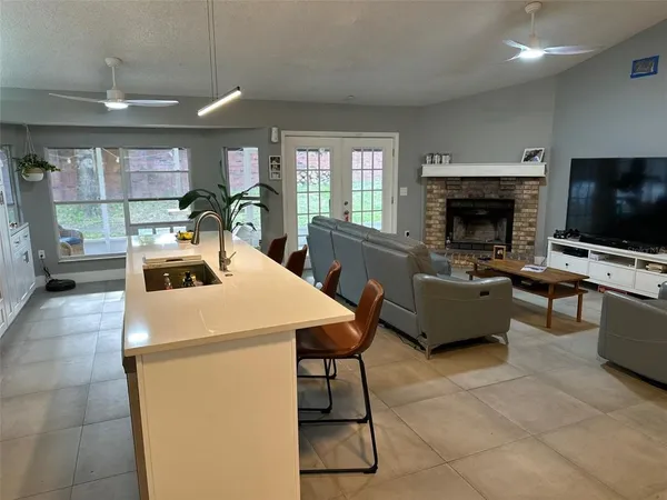 a living room with stainless steel appliances a couch a stove a kitchen island and chairs in it