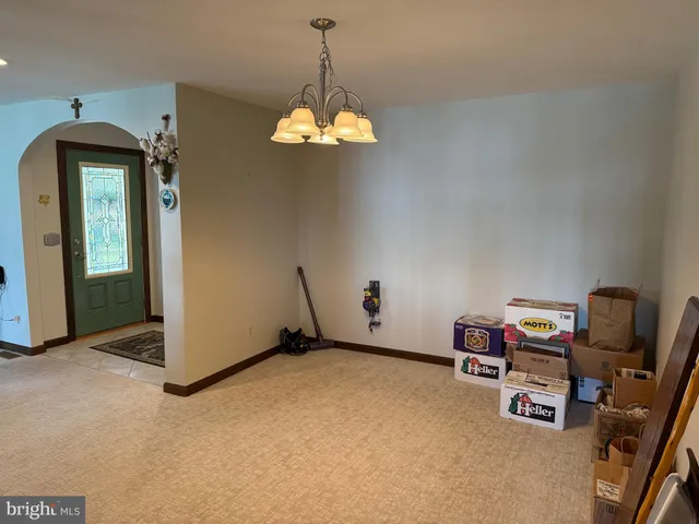 a view of a room with a hanging light and hardwood