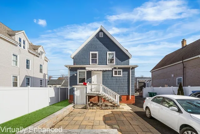 a view of a white house with a small yard and potted plants