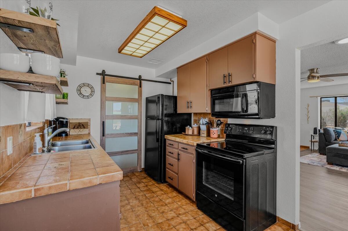 63555 Walpi Drive Joshua Tree, CA 92252 - Photo 11 of 30 a kitchen with stainless steel appliances a stove microwave and a refrigerator
