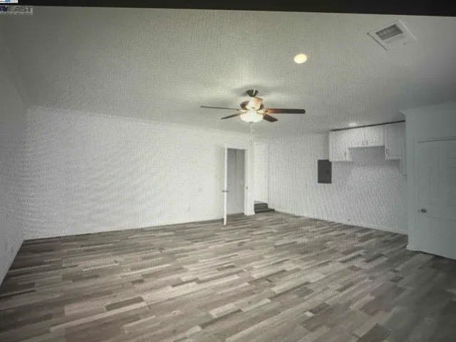 a view of an empty room with a chandelier fan