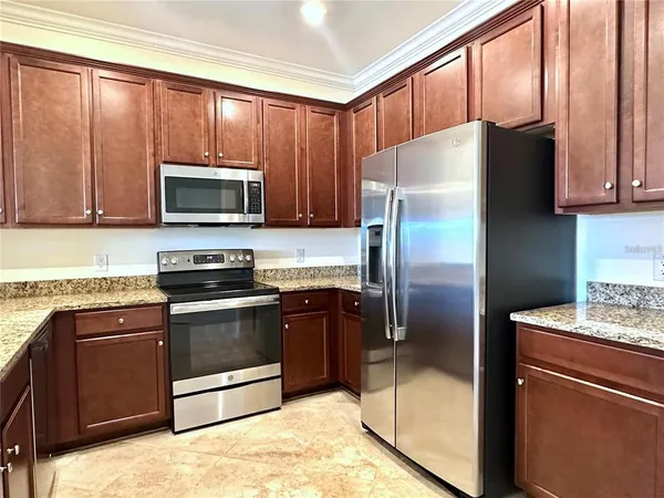 a kitchen with granite countertop a refrigerator stove and microwave