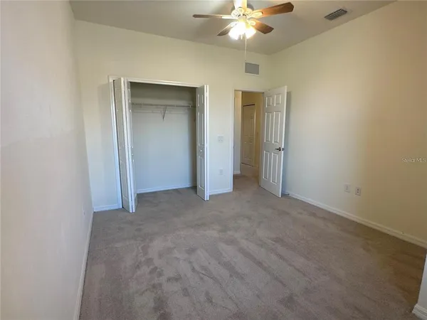 a view of an empty room with a chandelier fan