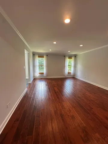 a view of an empty room with wooden floor and window