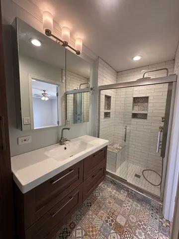 a bathroom with a sink a toilet a mirror and shower