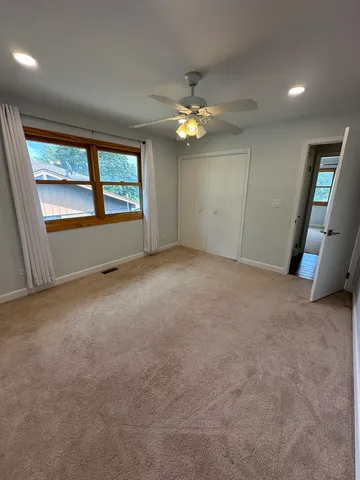 an empty room with windows and fan