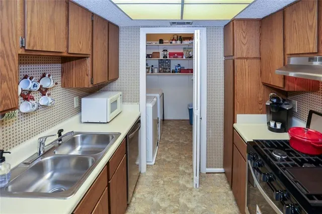 a kitchen with stainless steel appliances a refrigerator a sink and cabinets