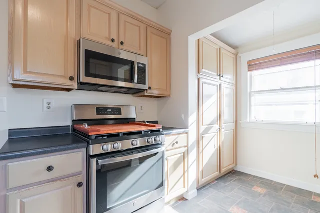 a kitchen with granite countertop white cabinets sink and a window