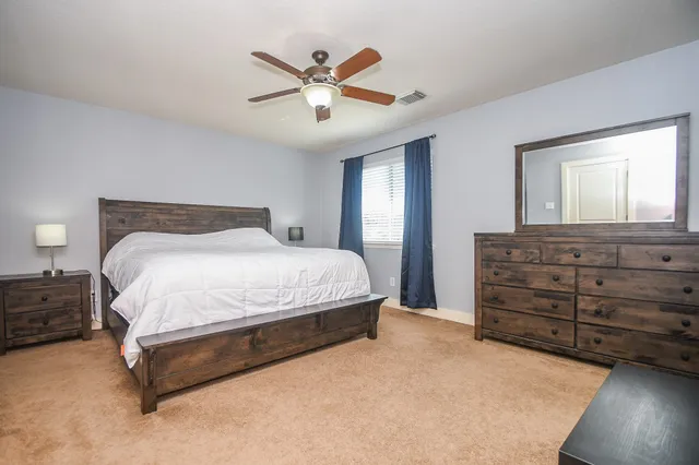 a spacious bedroom with a bed and a dresser