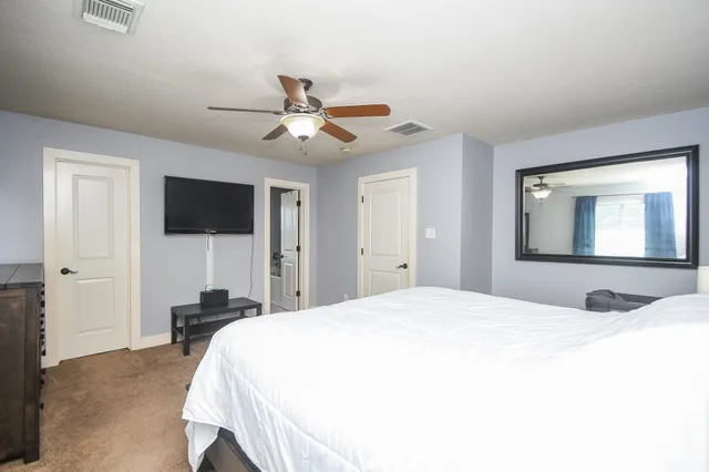 a bedroom with a bed and a flat tv screen on dresser