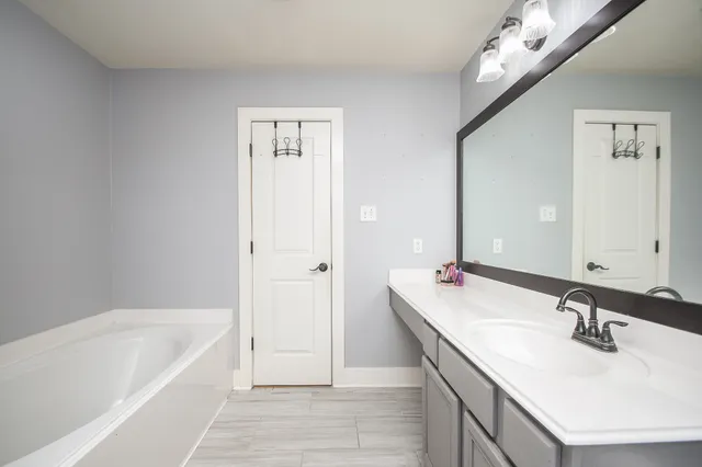 a bathroom with a tub sink and mirror