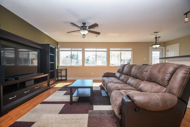 a living room with furniture a ceiling fan and a flat screen tv