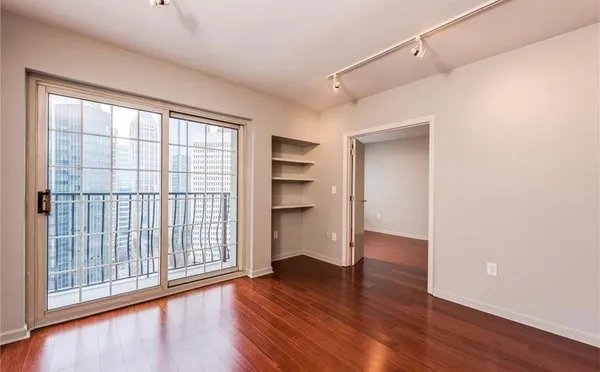 a view of an empty room with a window and wooden floor