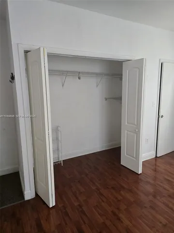 an empty room with wooden floor and closet