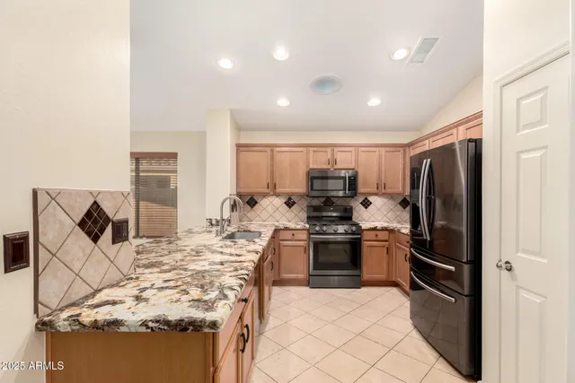 a kitchen with stainless steel appliances kitchen island granite countertop a refrigerator and a stove top oven