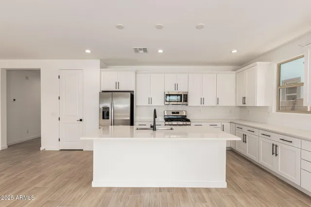 a kitchen with stainless steel appliances a refrigerator a stove top oven and white cabinets