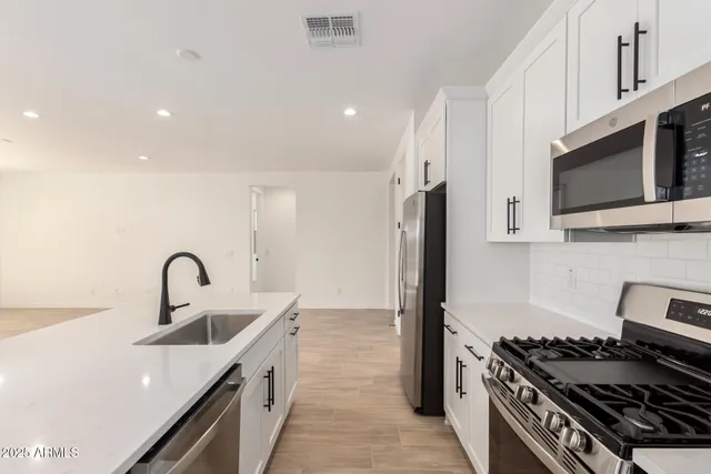 a kitchen with stainless steel appliances kitchen island a stove and a sink