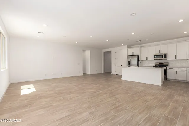 a view of a kitchen with kitchen island a sink wooden floor and white appliances