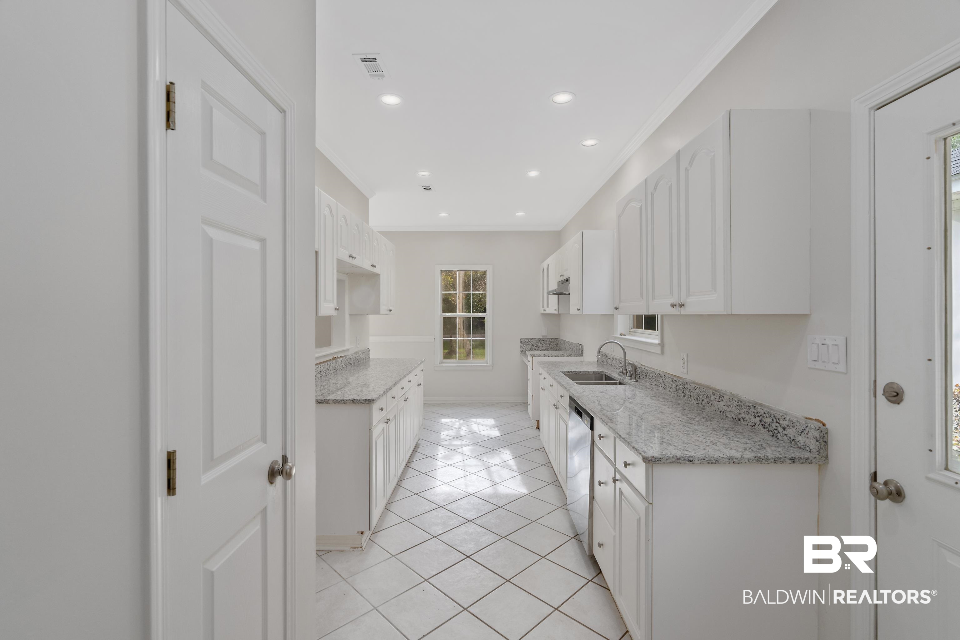 20525 Lawrence Road Fairhope, AL 36532 - Photo 10 of 26 Kitchen featuring sink, white cabinetry, light tile patterned floors, and light stone counters