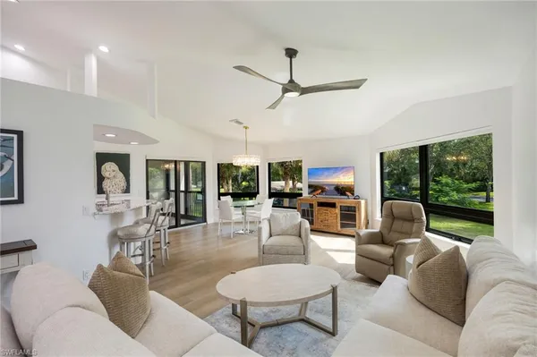 a living room with furniture a flat screen tv and a large window