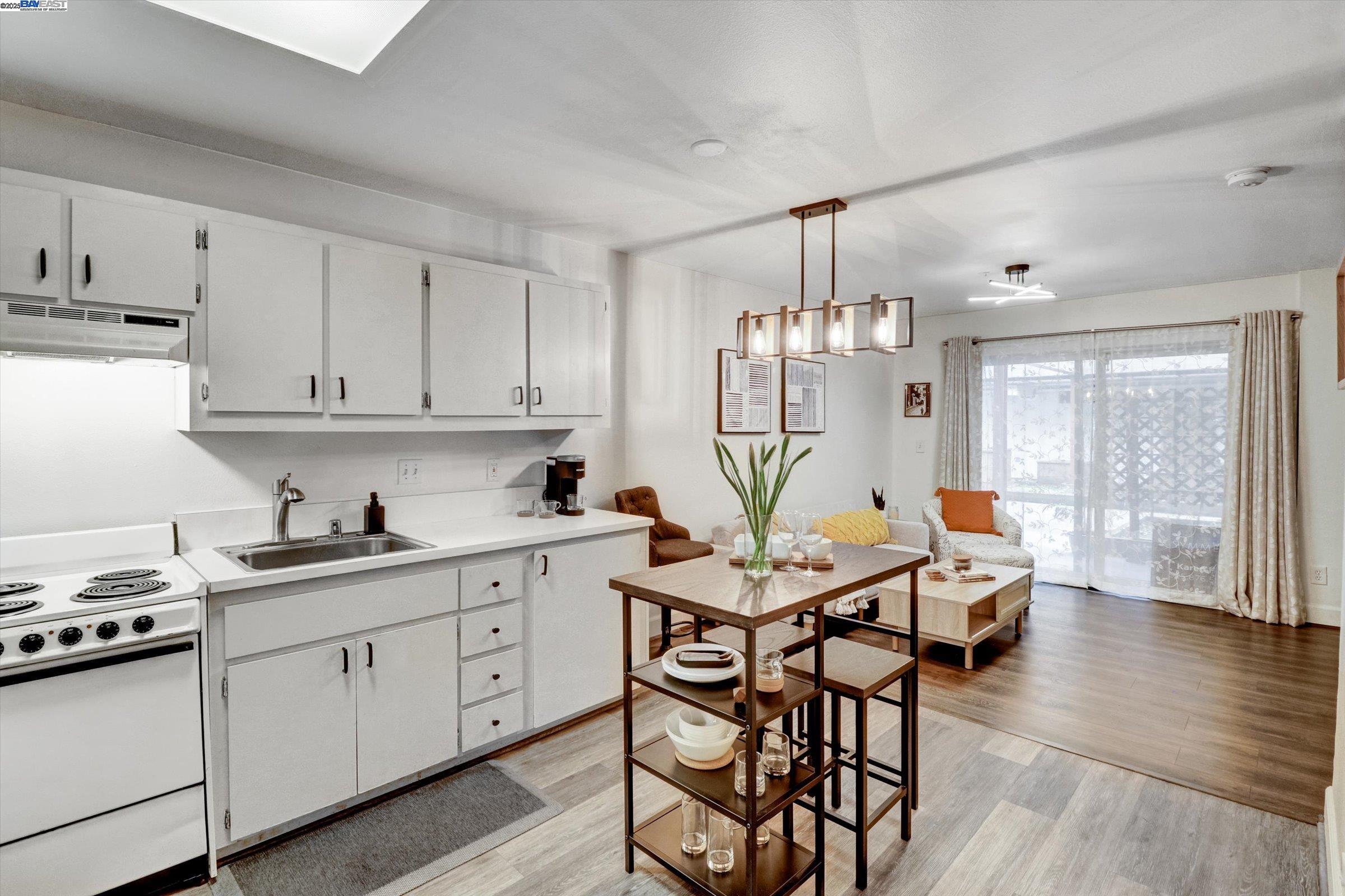 a kitchen with stainless steel appliances granite countertop a stove top oven a sink dishwasher and white cabinets with wooden floor