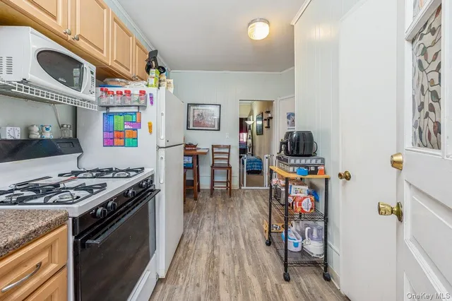 a kitchen that has a lot of cabinets a stove and wooden floor