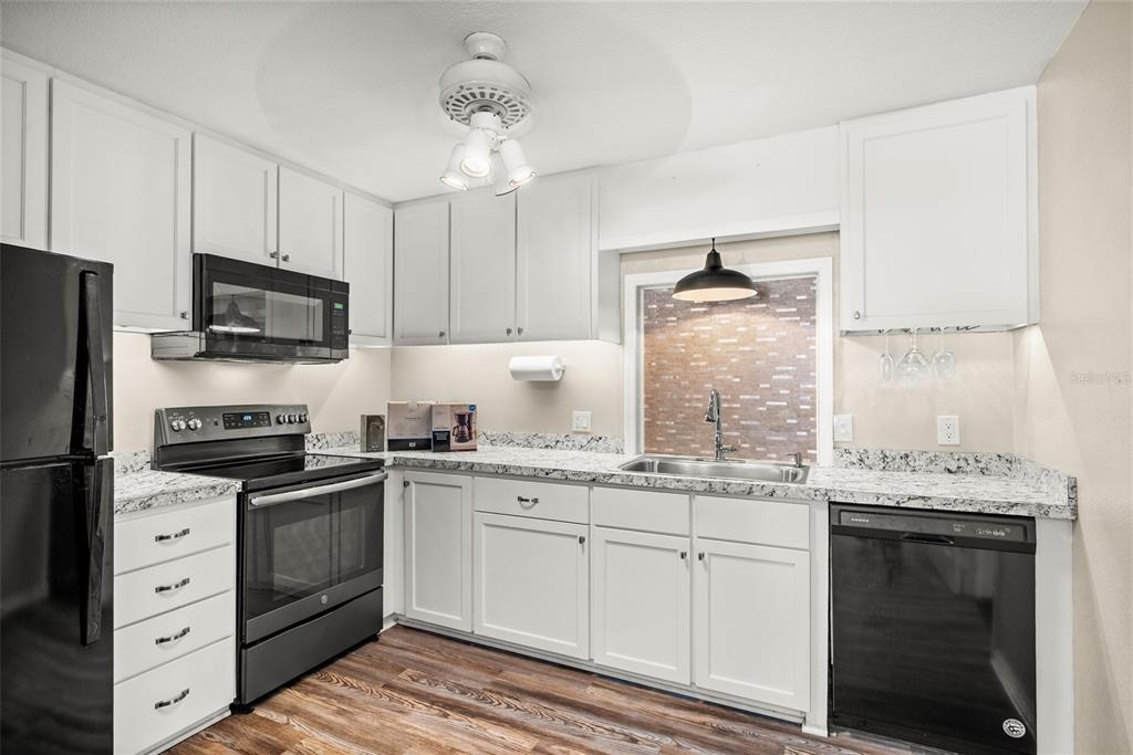 435 3rd Street Northwest Largo, FL 33770 - Photo 7 of 35 a kitchen with granite countertop a sink stainless steel appliances and white cabinets