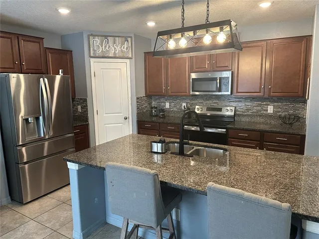 a kitchen with stainless steel appliances granite countertop a sink refrigerator and microwave