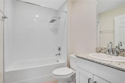 a bathroom with a granite countertop sink a toilet and shower