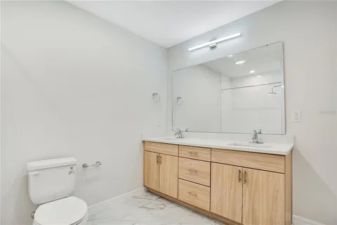 a bathroom with a granite countertop toilet sink and mirror