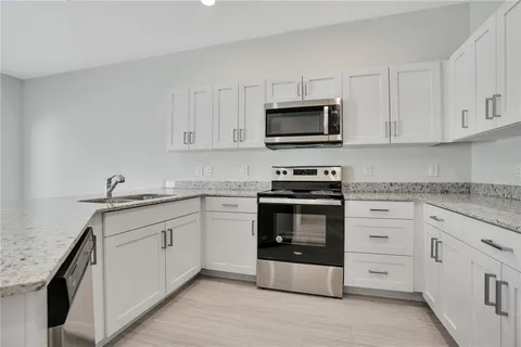a kitchen with white cabinets stainless steel appliances and sink